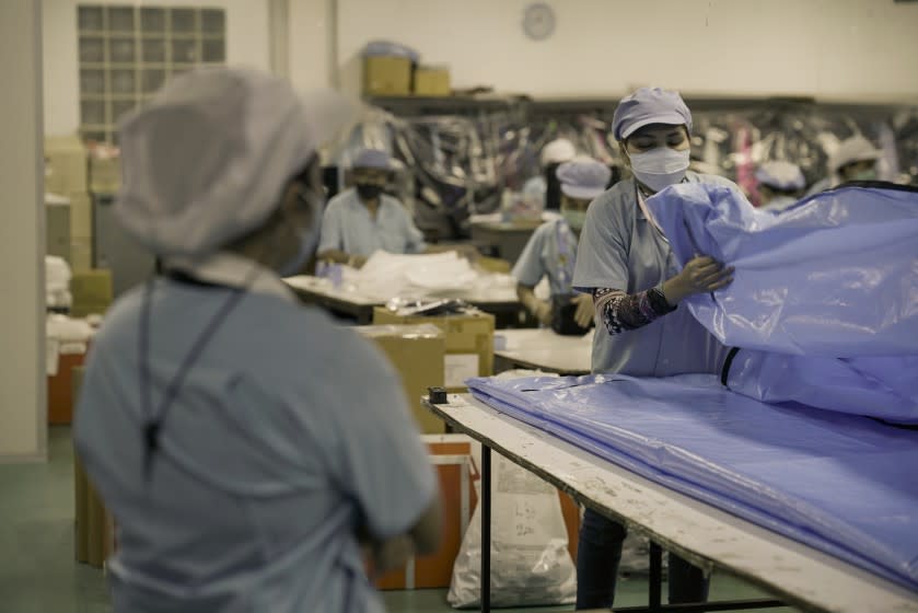 About 200 workers bustle around Winbest Industrial factory in Thailand as they manufacture shower caps, ponchos and aprons — and body bags. <span class="copyright">(Caleb Quinley / For The Times)</span>