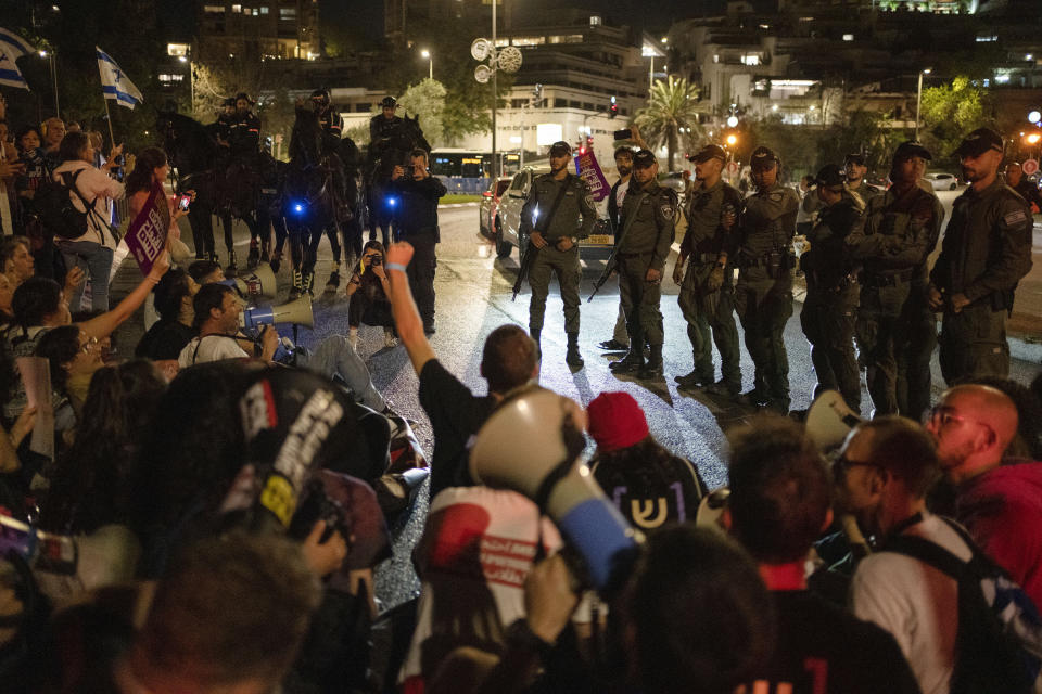 Police officers stand in front of people sitting on the street during a protest against Israeli Prime Minister Benjamin Netanyahu's government and call for the release of hostages held in the Gaza Strip by the Hamas militant group near the Knesset, Israel's parliament, in Jerusalem, Monday, April 1, 2024. (AP Photo/Leo Correa)