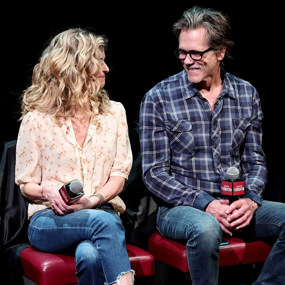 Kevin Bacon and Kyra Sedgwick smiling at each other while sat on stage being interviewed