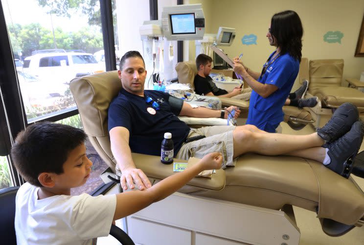 Damon Friedburg shows his son Kellen, 12, how he is giving blood at the OneBlood center in Orlando on June 13. (Joe Burbank/Orlando Sentinel via AP)