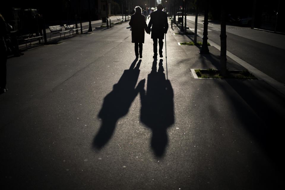 A couple walk along a boulevard in Barcelona, Spain, Sunday, Jan. 17, 2021. Scientists say it's still too early to predict the future of the coronavirus, but many doubt it will ever go away entirely. (AP Photo/Emilio Morenatti)