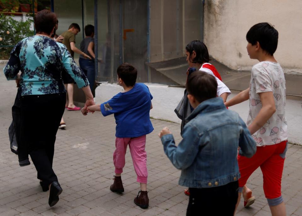 Teacher Irina Nikolaeva Ogurtsova leads children to a basement shelter as an air raid warning goes off at the facility (Reuters)