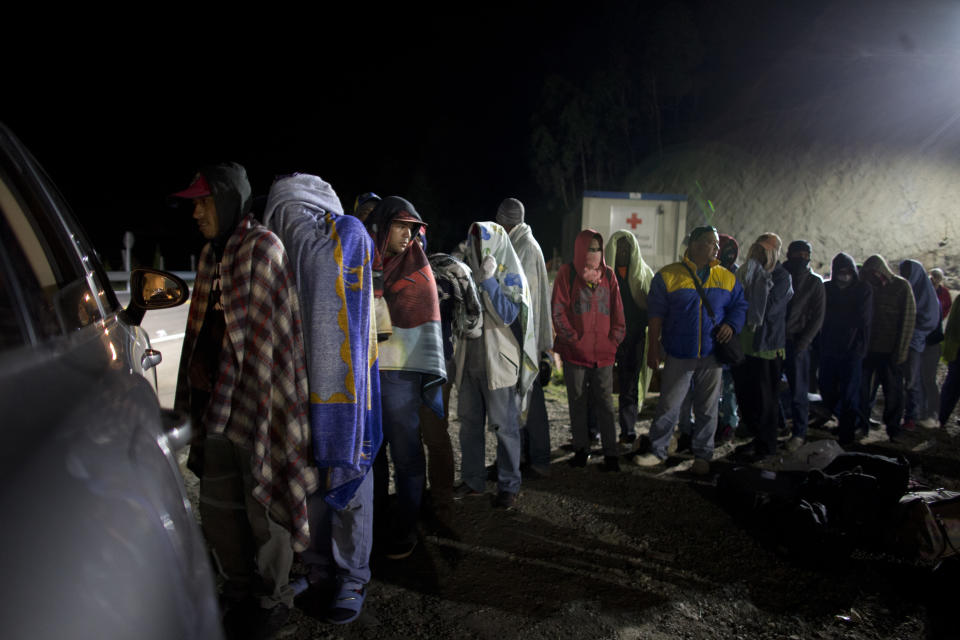 In this Aug. 31, 2018 photo, Venezuelan migrants line up for free bread and coffee, donated by a Colombian family from their car, at a gas station in Pamplona, Colombia. Millions have fled Venezuela's deadly shortages and spiraling hyperinflation in an exodus that rivals even the European refugee crisis in numbers. (AP Photo/Ariana Cubillos)