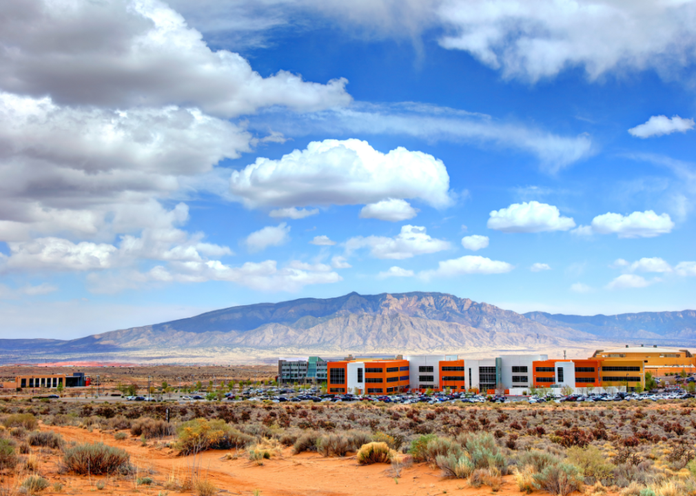 Modern buildings in vast barren land with tall mountains in the background.