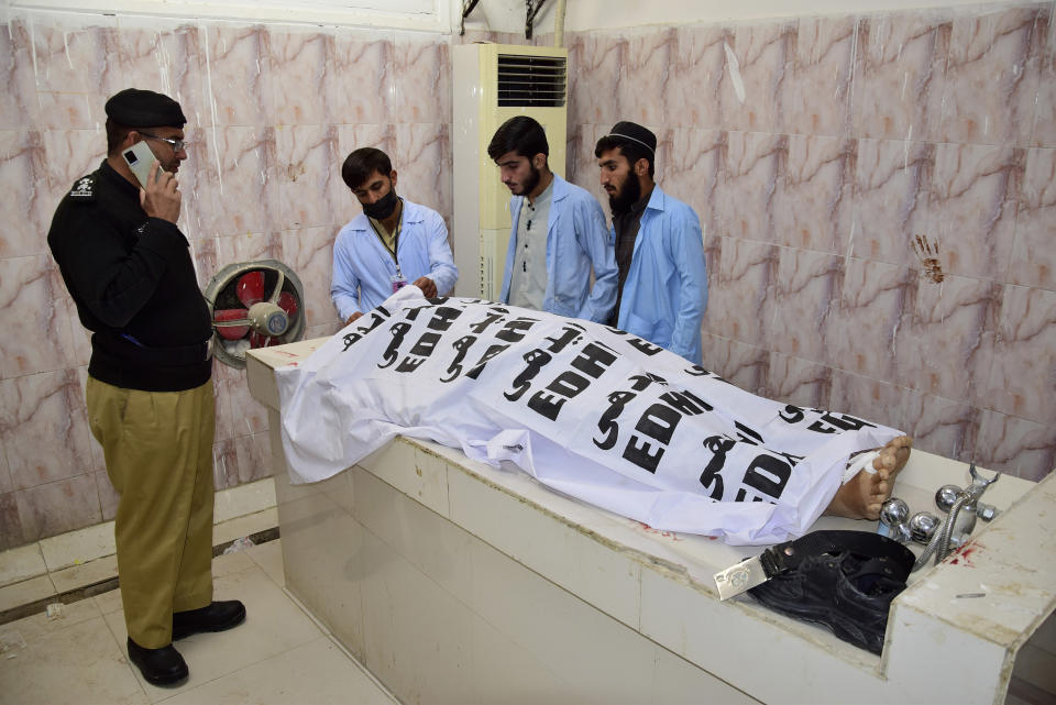 Hospital staff cover the body of a victim of a suicide bombing in Quetta, Pakistan, Wednesday, Nov. 30, 2022. A suicide bomber blew himself up near a truck carrying police officers on their way to protect polio workers outside Quetta officials said. (AP Photo/Arshad Butt)