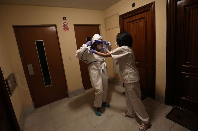 Comunidad de Madrid home care nurse Ana Arenal helps home care nurse Maria Jesus Santamaria with taking off her protective suit after treating a COVID-19 patient in Madrid