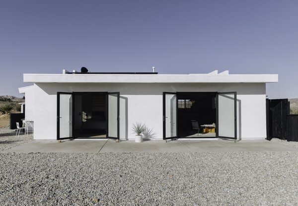 Sleek black-framed glass doors open the off-grid home up to its serene desert landscape.