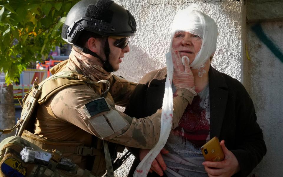 An injured woman receives medical treatment at the scene of Russian shelling, in Kyiv - AP