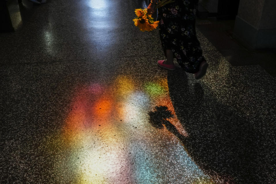The shadow of a person carrying an offering of sunflowers enters the shrine of the Virgin of Charity of El Cobre in El Cobre, Cuba, Sunday, Feb. 11, 2024. The Vatican-recognized Virgin, venerated by Catholics and followers of Afro-Cuban Santeria traditions, is at the heart of Cuban identity, uniting compatriots from the Communist-run Caribbean island to those who were exiled or emigrated to the U.S. (AP Photo/Ramon Espinosa)