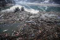 Boats push tons of garbage stuck at the foot of the hydro power plant at the Potpecko accumulation lake near Priboj, in southwest Serbia, Friday, Jan. 22, 2021. Serbia and other Balkan nations are virtually drowning in communal waste after decades of neglect and lack of efficient waste-management policies in the countries aspiring to join the European Union. (AP Photo/Darko Vojinovic)