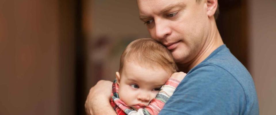 The father holds on hands of the little sad baby. Family concept. At the baby teeth are cut.