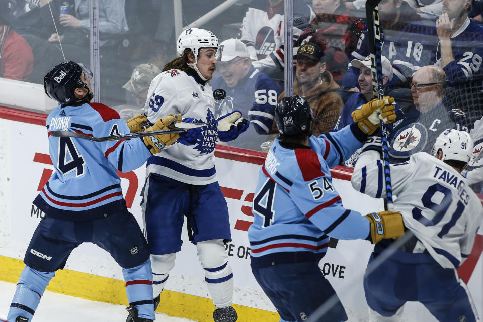 Winnipeg Jets' Neal Pionk (4) defends against Toronto Maple Leafs' Tyler Bertuzzi (59) during the first period of an NHL hockey game, Saturday, Jan. 27, 2024, in Winnipeg, Manitoba. (John Woods/The Canadian Press via AP)