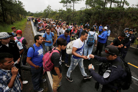 Honduran migrants show their identification to the officials near to the Agua Caliente border, hoping to cross into Guatemala and join a caravan trying to reach the U.S, in the municipality of Ocotepeque, Honduras October 17, 2018. REUTERS/Jorge Cabrera