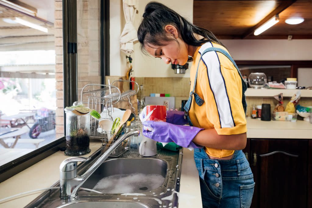A teenager cleans dishes. 