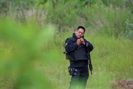 A police officer keeps watch near a clandestine grave while officials resumed the search for human remains after authorities found bodies packed in plastic bags, in the municipality of Zapopan