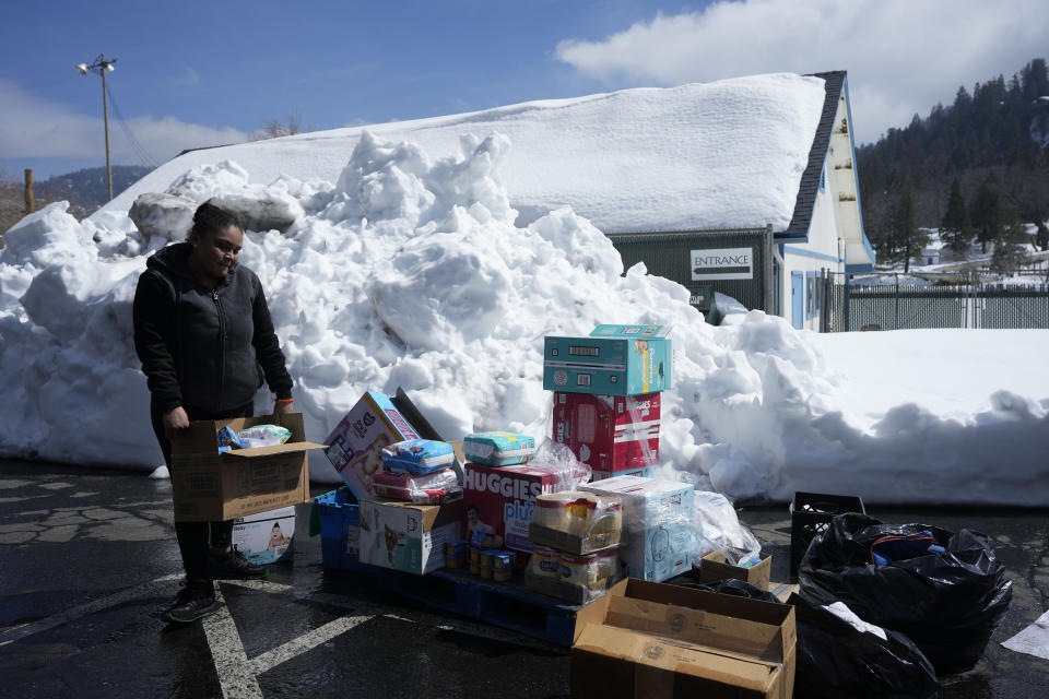 A woman picks up supplies at a distribution center out of a parking lot after a series of storms, Wednesday, March 8, 2023, in Crestline, Calif. (AP Photo/Marcio Jose Sanchez)