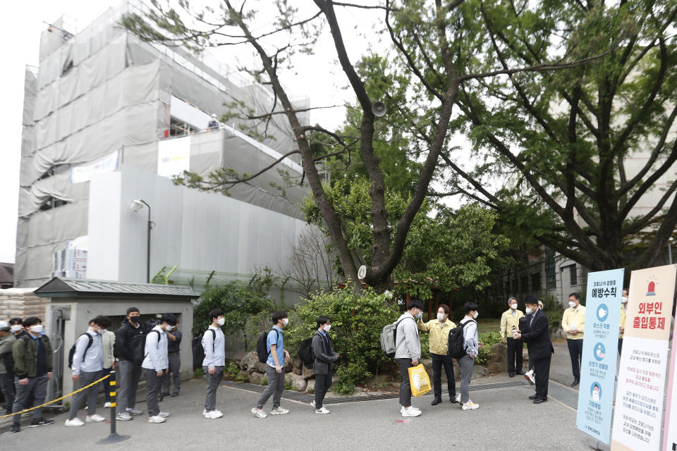 Senior students line up to get their body temperatures checked at the Kyungbock High School in Seoul, South Korea, Wednesday, May 20, 2020. South Korean high schools reopened on Wednesday after weeks of postponement due to safety concerns over the coronavirus outbreak. (AP Photo/Ahn Young-joon)