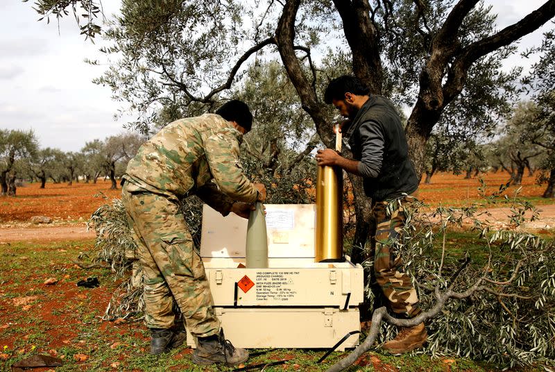 Syrian fighters prepare shell cases to an artillery near Idlib