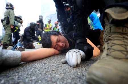 A man lies down as he's being detained by riot police officers while anti-government protesters demonstrate in Admiralty district, Hong Kong