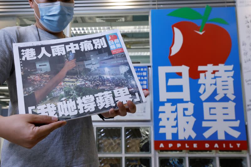 A staff member of Apple Daily poses with his final edition of Apple Daily at its headquarters in Hong Kong