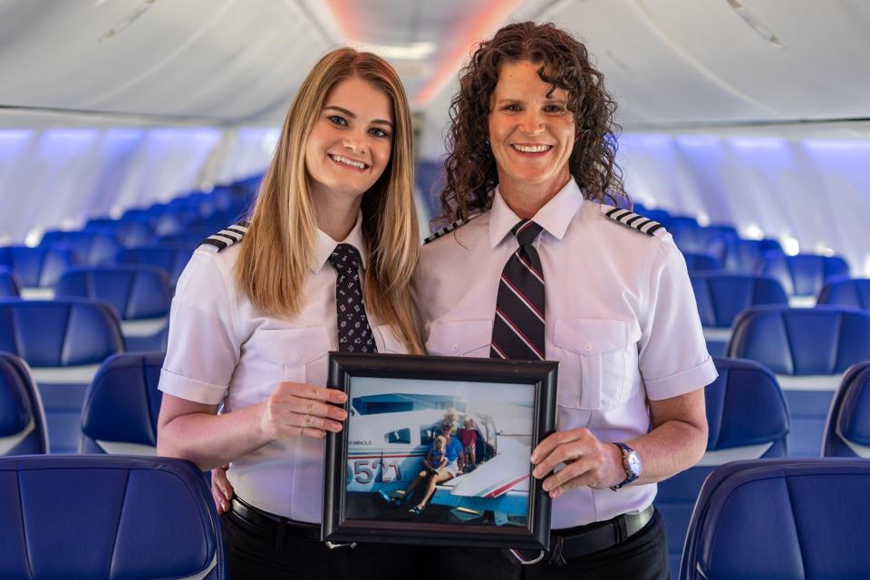 Keely and Holly Petitt holding an archival photo of the Petitt family on an airplane wing