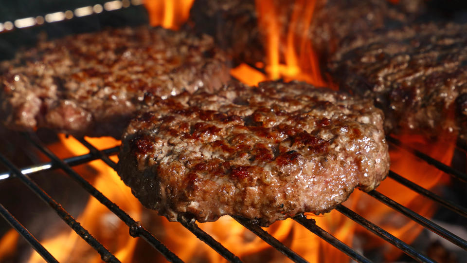 Burgers cooking on a flaming grill