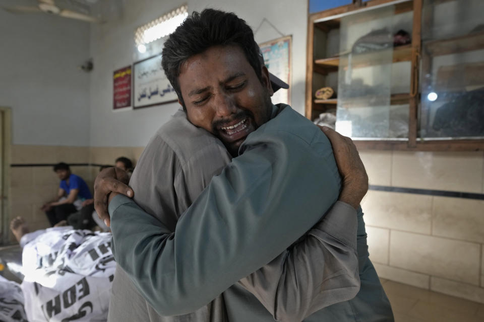 People mourn next to the bodies of fire fighters who died in a fire, at a morgue in Karachi, Pakistan, Thursday, April 13, 2023. A massive fire broke out in a garment factory in the southern Pakistan port city of Karachi. The cause of the blaze, which ripped through the factory Wednesday night and eventually caused it to collapse, was not immediately known, rescue officials and police said. (AP Photo/Fareed Khan)