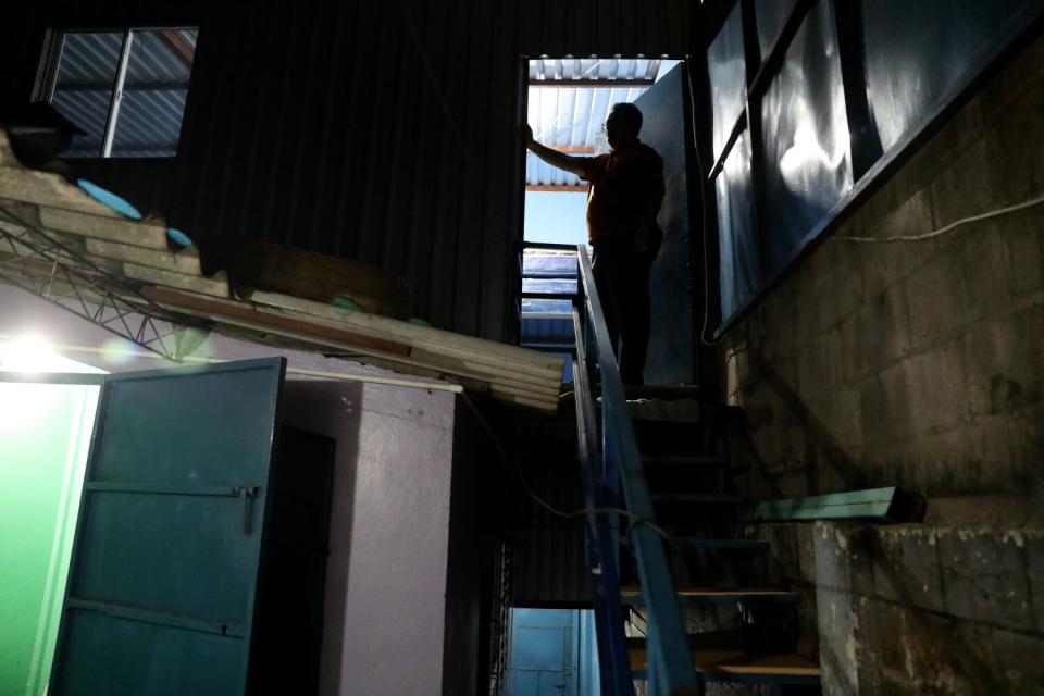 A person standing on basement stairs near an open door