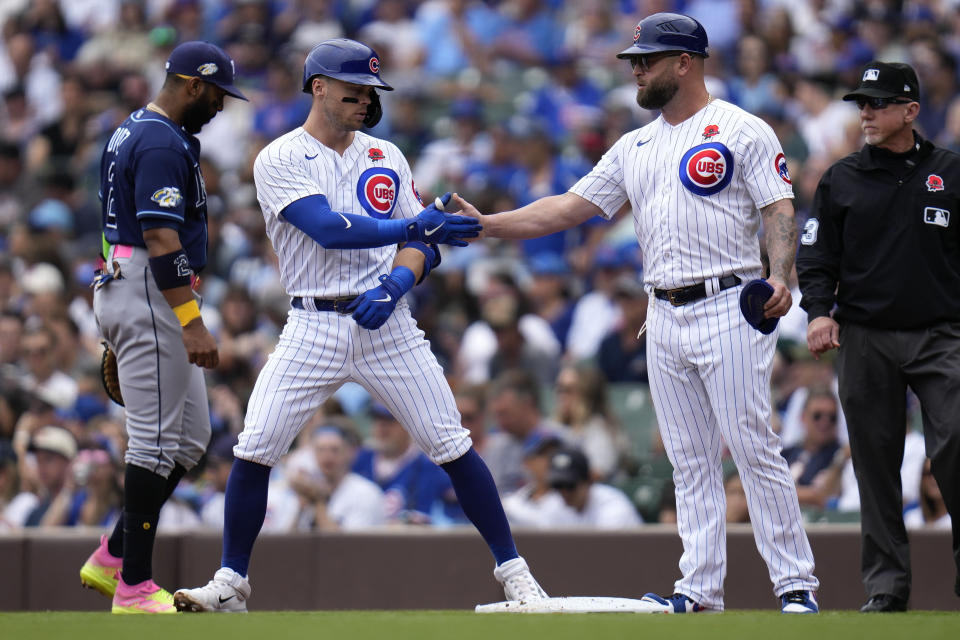 Chicago Cubs' Nico Hoerner, left, slaps hands with first base coach Mike Napoli after hitting a single during the first inning of a baseball game against the Tampa Bay Rays Monday, May 29, 2023, in Chicago. (AP Photo/Erin Hooley)