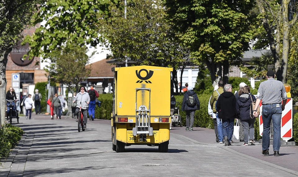 In this photo taken on Wednesday, May 15, 2019, an electric vehicle of Deutsche Post drives beside pedestrians on the environmental island of Langeoog in the North Sea, Germany. Concerns about climate change have prompted mass protests across Europe for the past year and are expected to draw tens of thousands onto the streets again Friday, May 24. For the first time, the issue is predicted to have a significant impact on this week’s elections for the European Parliament. (AP Photo/Martin Meissner)
