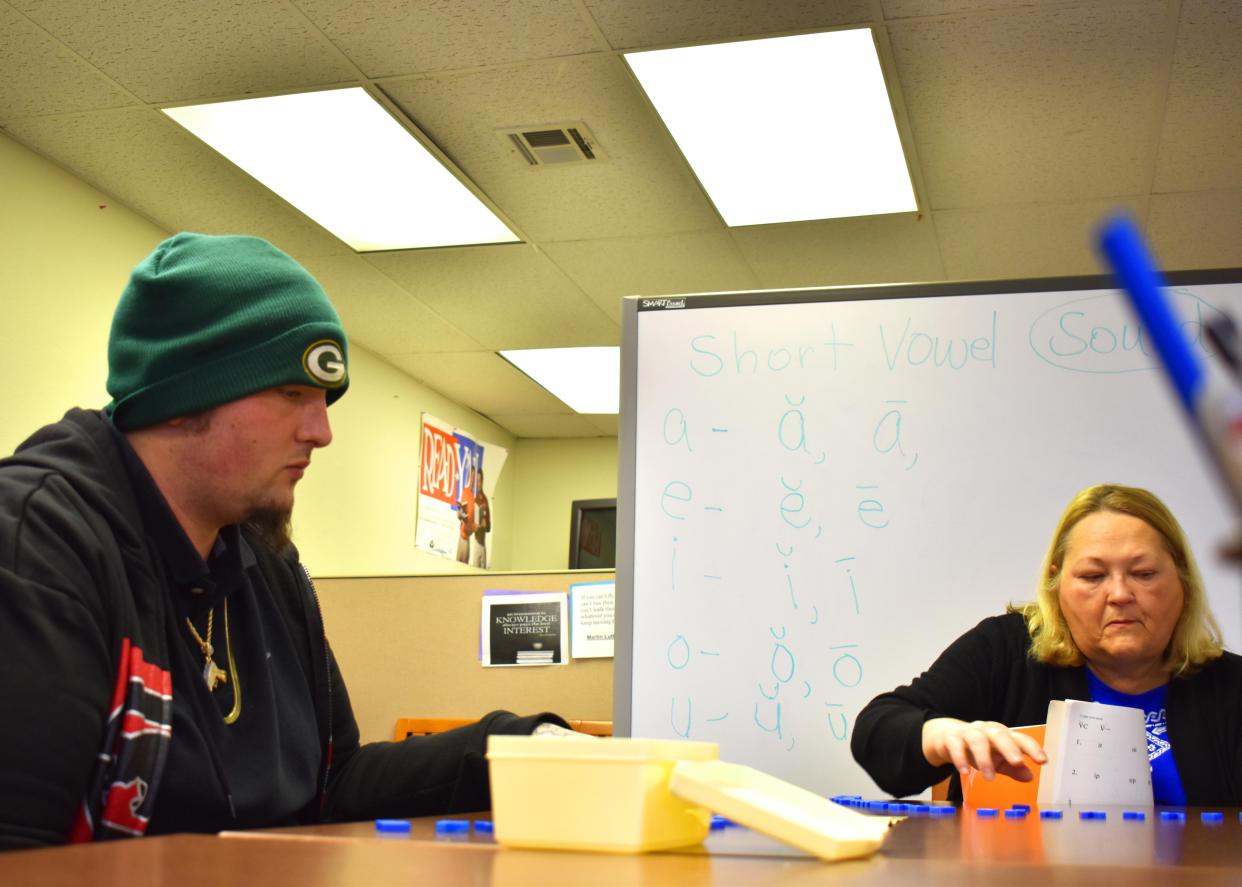 A tutor works with a man arranging letters to form words during an adult literacy class.