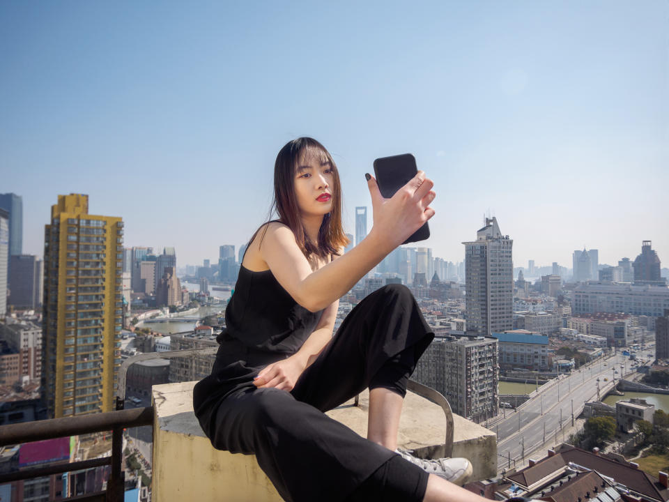 A young woman taking a selfie on top of a building.