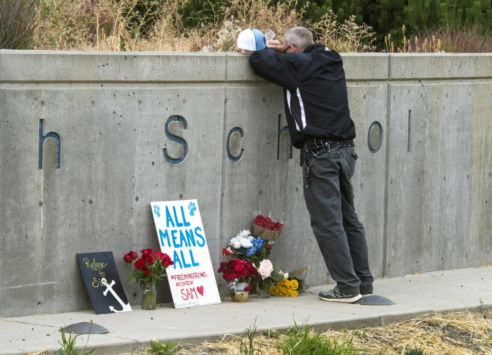 FILE - In this Sept. 14, 2017, file photo, Freeman High School assistant football coach Tim Smetana grieves after he placed roses at a memorial following a shooting at the school in Rockford, Wash. A judge in Washington state will decide if a youth charged with shooting four classmates at Freeman High, killing one, will be tried as an adult. Closing arguments were held Monday, July 22, 2019, in a week-long hearing for 17-year-old Caleb Sharpe. (Dan Pelle/The Spokesman-Review via AP, File)
