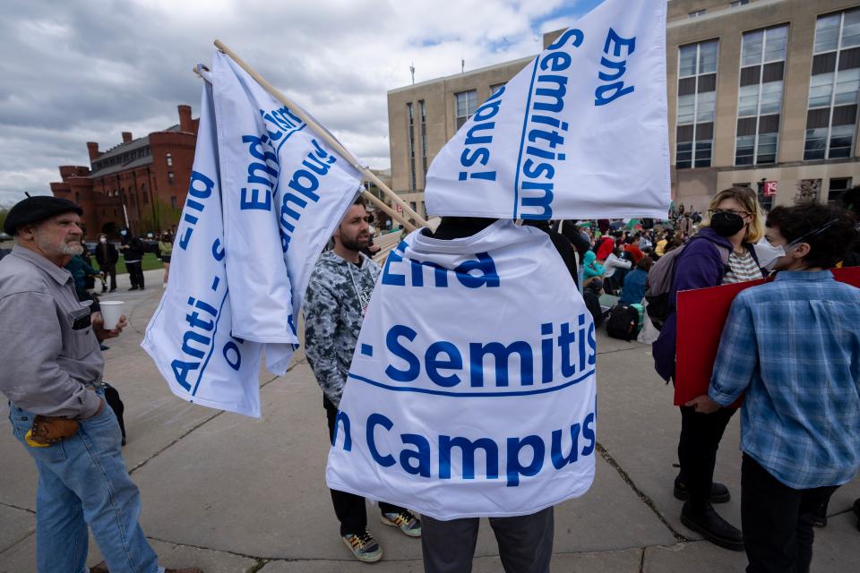 Erik Olsen, a UW-Madison alumnus who is Jewish, carries a sign that reads, "End Anti-Semitism On Campus" as he walks among pro-Palestinian demonstrators at the University of Wisconsin-Madison on Monday.