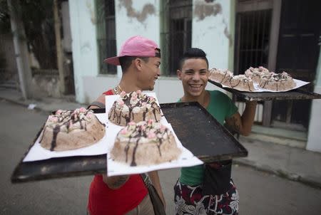 Emanuel Gonzales, 19 (L), and Emanuel Perez, 17, carry home-baked cakes for sale on the streets of downtown Havana January 9, 2015. REUTERS/Alexandre Meneghini