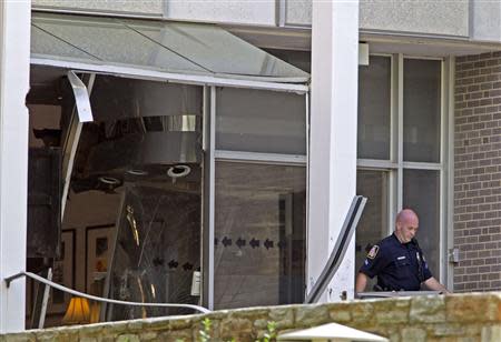 A Baltimore county police officer walks out the broken door at the entrance of the WMAR-TV station, after a possibly armed man crashed a truck into the Maryland television news station and barricaded himself inside the building, in Towson, Maryland May 13, 2014. REUTERS/Jose Magana