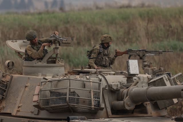 <p>Ilia Yefimovich/picture alliance via Getty </p> Israeli soldiers ride a tank near the Israel-Gaza border on Oct. 9, 2023