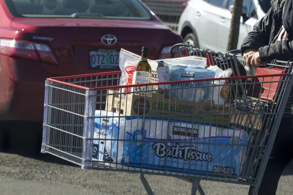 Tigard, OR, USA - Mar 17, 2020: A shopper pushing a cart loaded with bath tissues and other groceries at a Costco Wholesale Store in Tigard, Oregon.