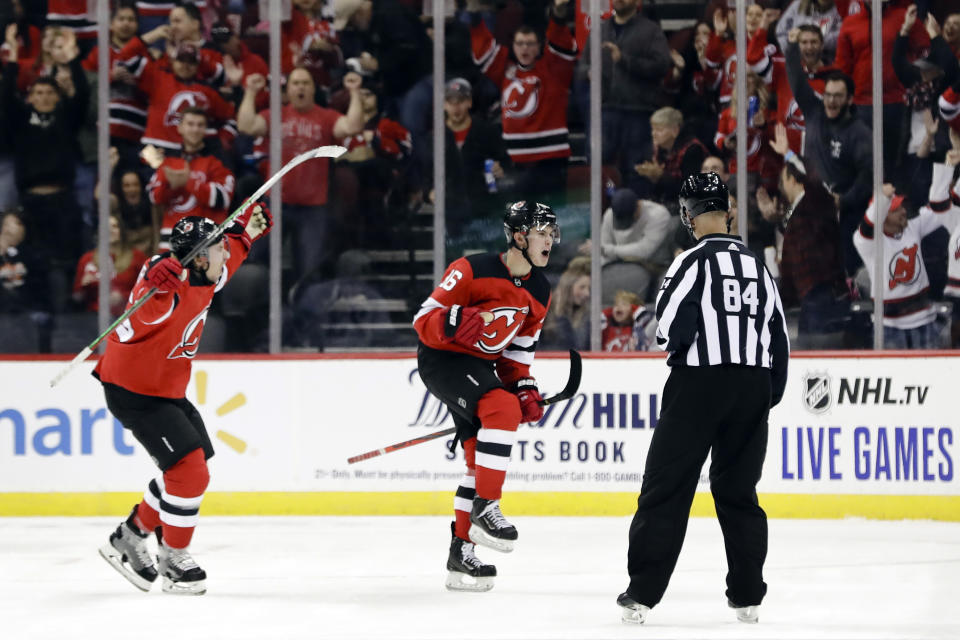 New Jersey Devils' Jack Hughes, center, celebrates with teammate Sami Vatanen, left, after scoring his first career NHL goal during the first period of a hockey game against the Vancouver Canucks, Saturday, Oct. 19, 2019, in Newark, N.J. (AP Photo/Frank Franklin II)