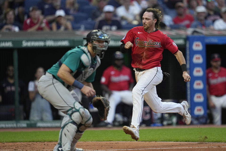 Cleveland Guardians' Daniel Schneemann, runs past Seattle Mariners catcher Cal Raleigh to score during the sixth inning of a baseball game Wednesday, June 19, 2024, in Cleveland. (AP Photo/Sue Ogrocki)