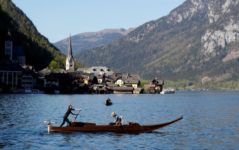 A boat floats at Hallstaettersee lake in front of the city of Hallstatt