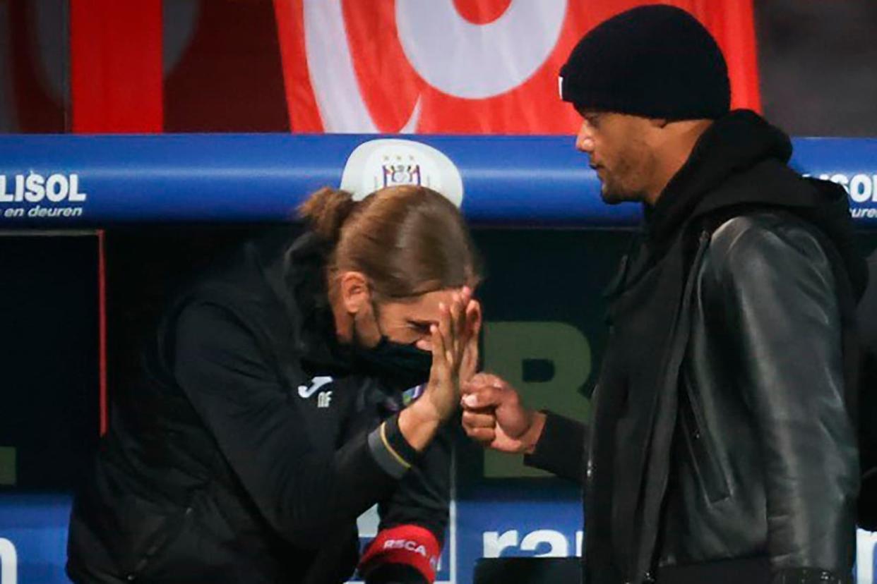 Nicolás Frutos choca las manos con Vincent Kompany en el banco durante un partido 