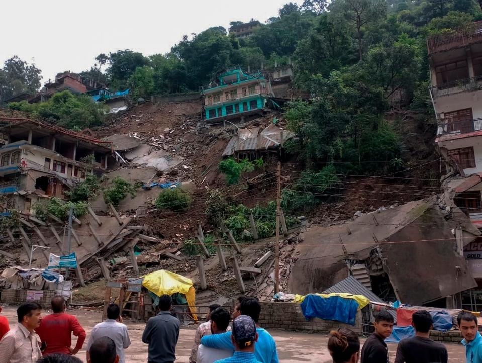 People look on after several buildings that had recently developed cracks and were evacuated, collapsed following heavy rains in Anni (AP)