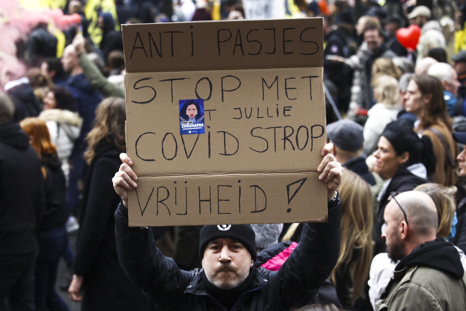 A man shows a poster reading: 'Against Passes. Stop the covid noose. Freedom' during a demonstration against the reinforced measures of the Belgium government to counter the latest spike of the coronavirus in Brussels, Belgium, Sunday, Nov. 21, 2021. Many among them also protested against the strong advice to get vaccinated and any moves to impose mandatory shots. (AP Photo/Olivier Matthys)