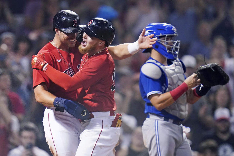 Boston Red Sox's Alex Verdugo, center, is congratulated by Hunter Renfroe, left, after his two-run home run in the eighth inning of a baseball game against the Toronto Blue Jays at Fenway Park, Monday, July 26, 2021, in Boston. Blue Jays catcher Reese McGuire, right, looks on. (AP Photo/Charles Krupa)