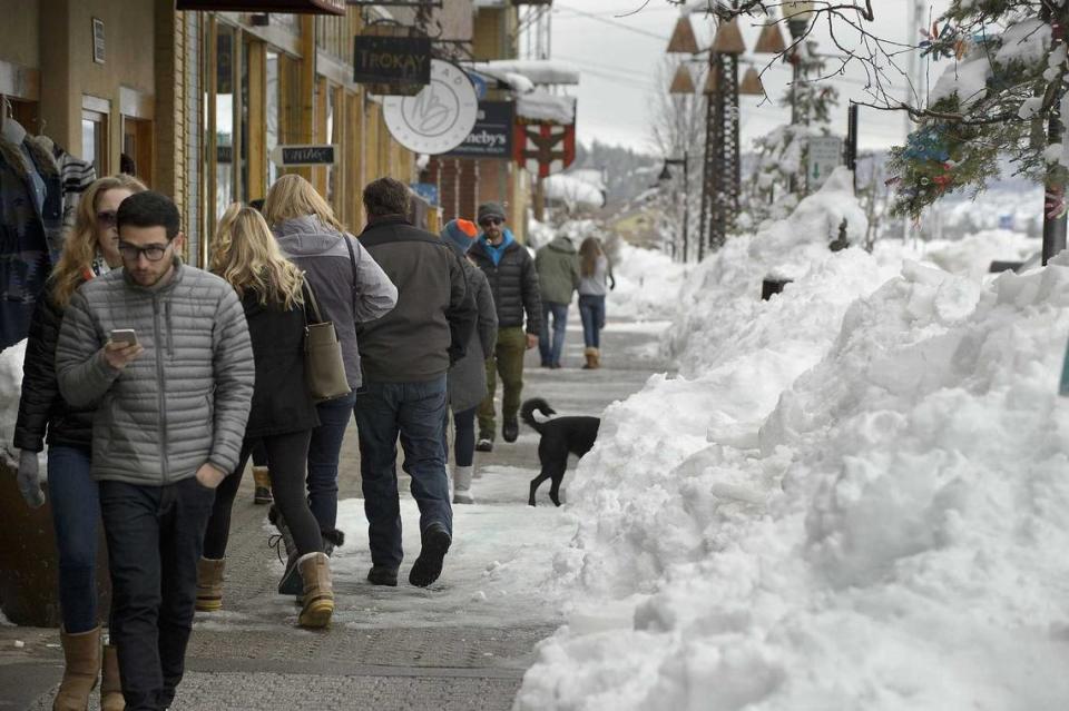 Shoppers walk along the sidewalk beside the snow piled up along Donner Pass Road in central Truckee in 2017. Tourism in the winter and summer are the lifeblood of the Tahoe-adjacent community. Donner Pass Road, the artery that preceded Interstate 80, faced weeks of closures during last year’s parade of winter storms.