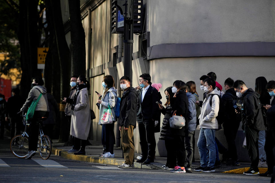 People wearing face masks wait at a traffic light to cross a street, as coronavirus disease (COVID-19) outbreaks continue in Shanghai, China, December 7, 2022. REUTERS/Aly Song