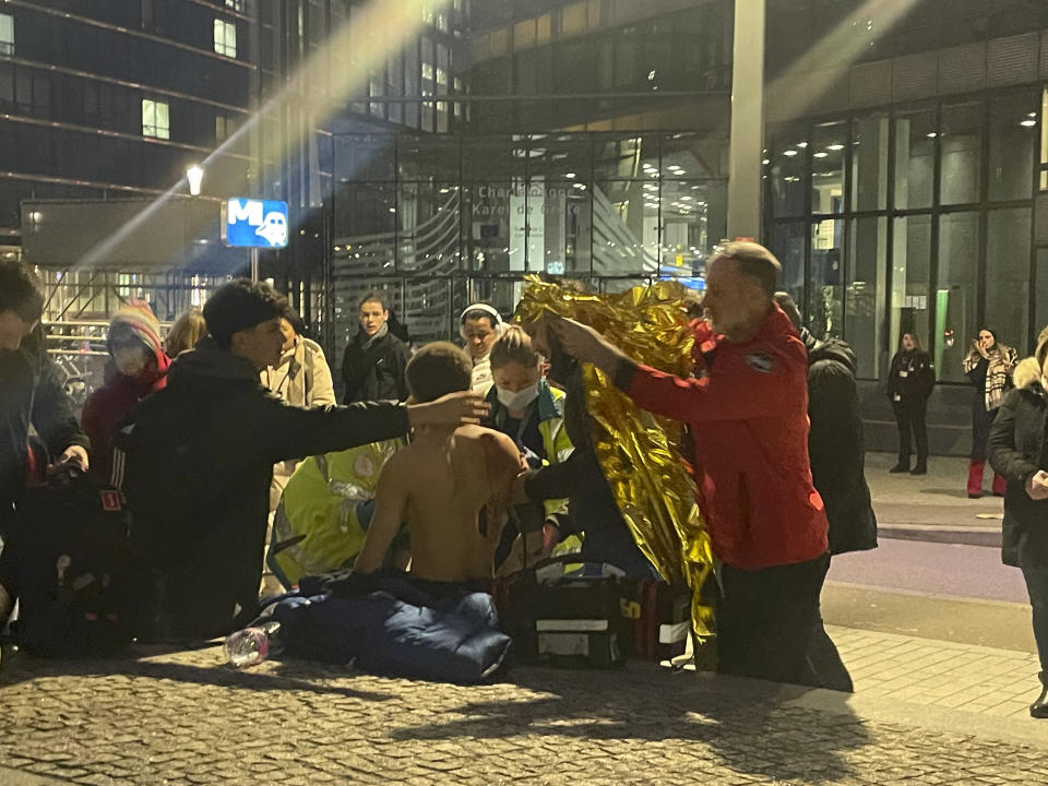 A man visibly wounded is helped by emergency personnel outside of a metro station near EU headquarters in Brussels, Monday, Jan. 30, 2023. News reports on Monday said that one man was injured in a knife incident around the European Union's headquarters in Brussels before one suspect was detained. (Jack Parrock via AP)