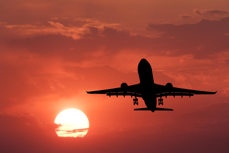 Silhouette of landing aircraft and red sky with sun. Landscape with passenger airplane is flying in the sky with clouds at sunset. Travel background. Passenger airliner. Commercial airplane. Business