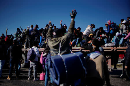 Migrants react as they pass by in the back of a truck during their journey towards the United States, in Mexico City, Mexico, January 31, 2019. REUTERS/Alexandre Meneghini